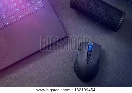 Gaming mouse portable speaker and laptop at night.