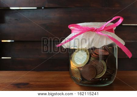 coins in the glass bottle on the wood background