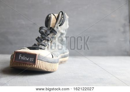 Follow me retro label for social networks and Vintage Sneakers on the table.