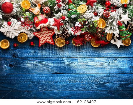 Merry Christmas Frame with green pine, colorful baubles, knots with berries,stars, orangesand other seasonal stuff over an old wooden aged background