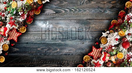 Merry Christmas Frame with green pine, colorful baubles, knots with berries,stars, orangesand other seasonal stuff over an old wooden aged background