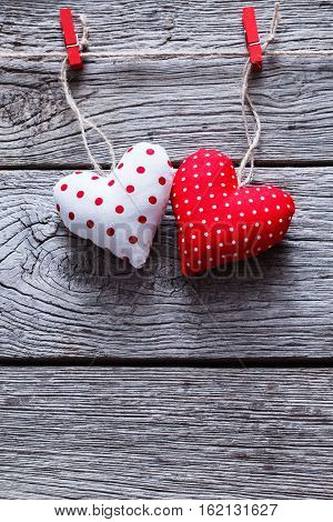 Valentine background with diy handmade sewed pillow hearts on red clothespins at rustic blue wood planks. Happy lovers day card mockup, copy space, vertical