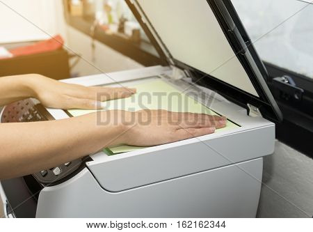 woman hands putting a sheet of paper into a copying device