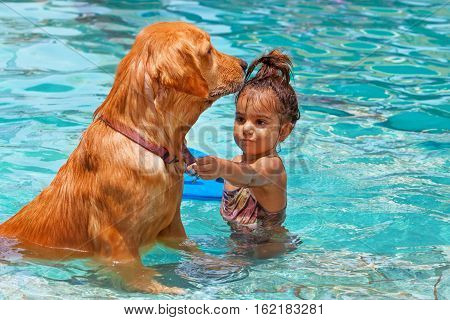 Funny photo of little baby swimming in outdoor pool playing with retriever puppy. Children water sports activity and swimming lessons training dogs fun games with family pet on summer vacation.