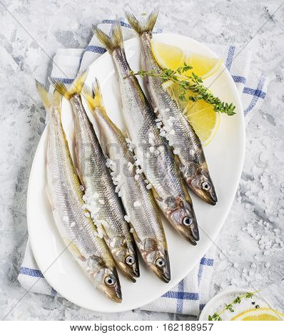 The freshest fish of the northern sea ice fishing smelt with the scent of fresh cucumber on a light background marble with lemon and herbs. Top view