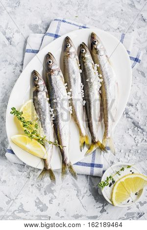 The freshest fish of the northern sea ice fishing smelt with the scent of fresh cucumber on a light background marble with lemon and herbs. Top view