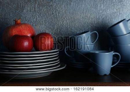 Set of dinnerware and fruits on gray background