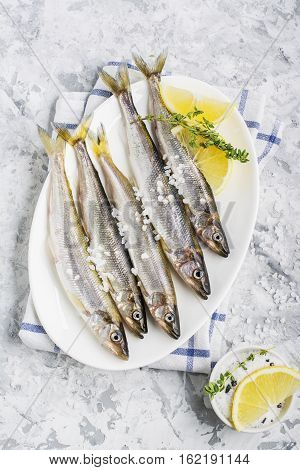 The freshest fish of the northern sea ice fishing smelt with the scent of fresh cucumber on a light background marble with lemon and herbs. Top view