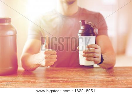 sport, fitness, healthy lifestyle and people concept - close up of man in fitness bracelet with protein shake bottle showing thumbs up