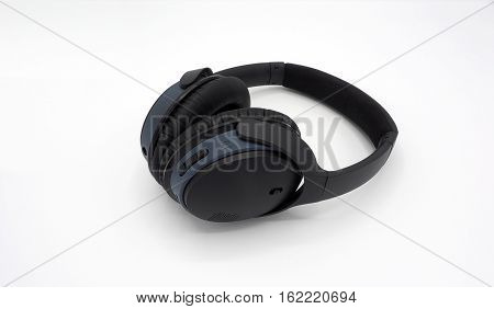 Black wireless headphone around ears and white background.