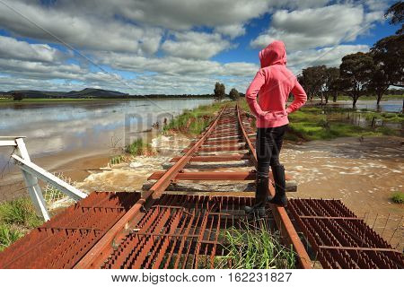 A female looks out over the floodwaters from the buckled train tracks at Crowther Hilltops Region Country NSW.
