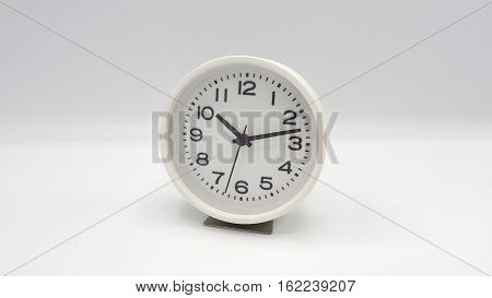 White clock with minute hand and hour hand on white background.