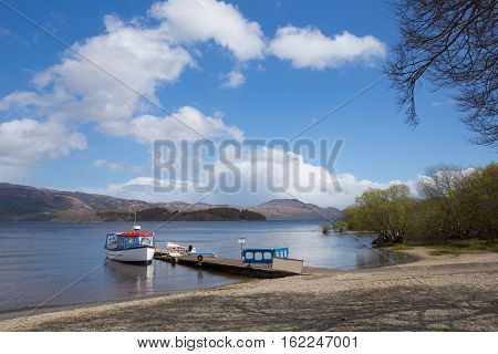 Loch Lomond Scotland UK in summer with blue sky boat and jetty popular Scottish tourist destination