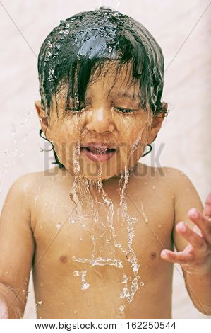 Happy baby in the bath face covered in water splash