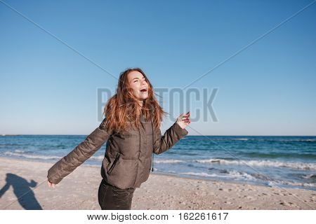 Laughing Woman dressed in warm jacket on date on beach near the sea. Side view