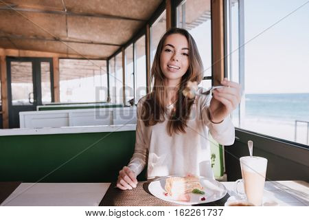 Woman on date with her man with coffee and cake in cafe near the sea
