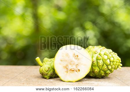 Noni fruit and noni slice on wooden table and green background.Fruit for health and herb for health.14