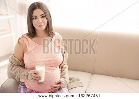 Beautiful pregnant woman drinking milk at home