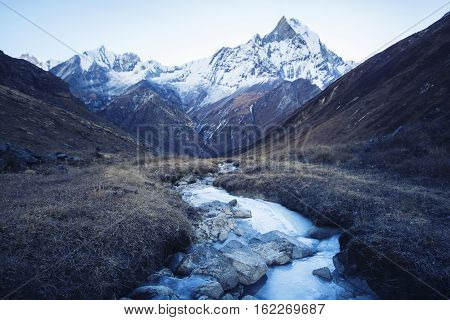 Stream with ice flowing down from the mountains blue shade of the morning light