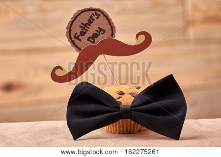 Muffin with mustache. Greeting card and bow tie. Delicious gift for daddy.