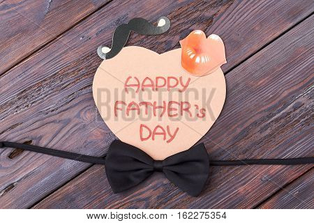 Black bow tie on wood. Card with lips and mustache. How to decorate greeting paper.