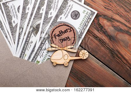 Wooden helicopter near dollar bills. Father's day card and bucks. Live a luxurious life.