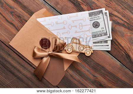 Dollar bills in sealed envelope. Car, bow, key print paper. Broad financial opportunities.