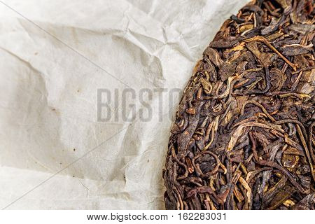 old Shen puerh chinese fermented tea on papyrus paper background with copyspace. Top view
