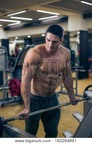 Muscular athletic bodybuilder fitness model posing after exercises in gym.