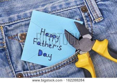 Pliers near Father's Day card. Jeans pocket with pliers. Masculine present for best daddy.