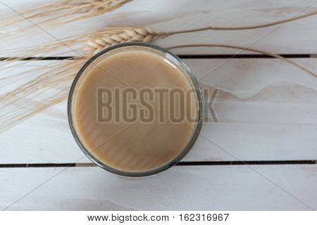 Traditional Drink from Balkan Peninsula Boza (fermented cereal beverage) and wheat over white wooden background