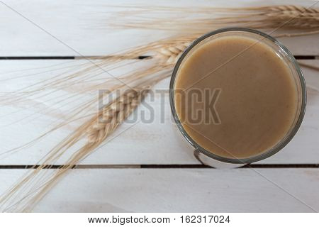 Traditional Drink from Balkan Peninsula Boza (fermented cereal beverage) and wheat over white wooden background