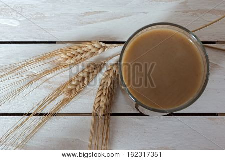 Traditional Drink from Balkan Peninsula Boza (fermented cereal beverage) and wheat over white wooden background