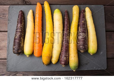Fresh organic rainbow carrots on a wooden table and slate blackboard