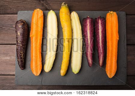 Fresh organic rainbow carrots on a wooden table and slate blackboard
