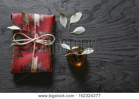 Red fabric present on a black wooden table with eucalyptus.