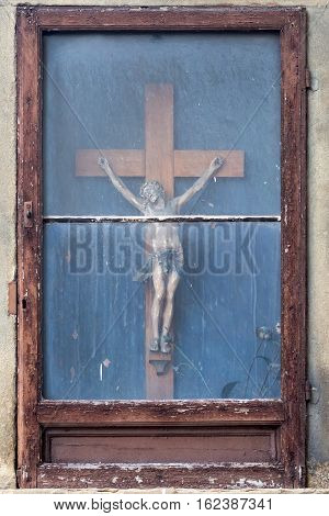 Jesus on the cross behind a window at an old house in Florence Italy