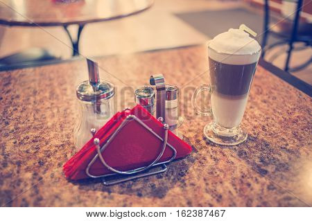 Coffee Latte in a glass on preshious bubingo-woood table, colorized vintage tones, shallow DOF, selective focus.