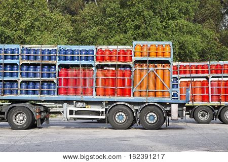 Trucks parked on a street load of colored propane gas tanks