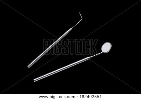 Dental mirror and dental sonde. Image isolated on black background.