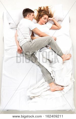 The young lovely couple lying in a white bed, love lconcept, top view