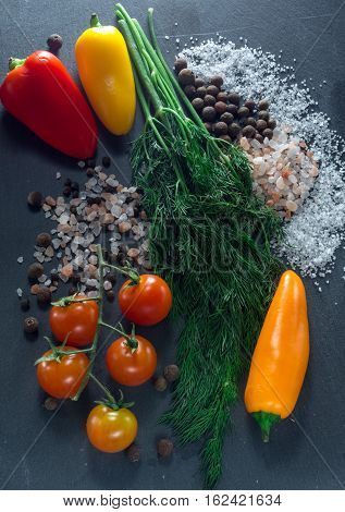 vegetables and spices on a black background, dill and pepper salt