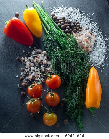 vegetables and spices on a black background, dill and pepper salt