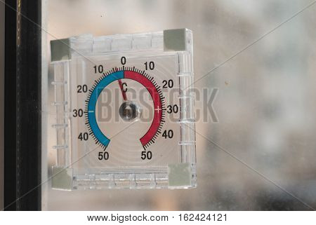 below zero on the old analogue thermometer, the concept of cold weather, the thermometer outside the window, frost on the yard