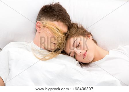 The young lovely couple lying in a white bed, love lconcept, top view