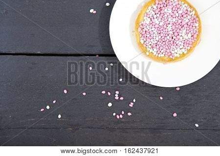 Traditional Dutch birth celebration biscuit with pink muisjes on wooden background
