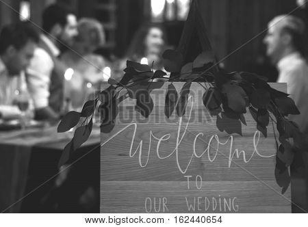 Wedding feast. Guests sit at festively decorated table. Evening candlelight. Black and white.