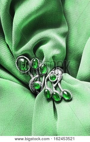 Vintage emerald silver ring on green silk as a background