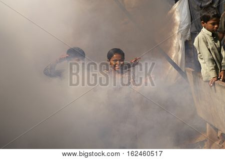 AHMADABAD, INDIA - OCTOBER 31, 2007: Children playing in a cloud of insecticide powder being sprayed amongst the dwellings of a shanty town in Ahmadabad, Gujarat, India.