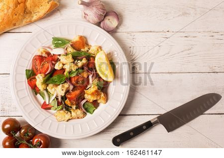 Italian Appetizer salad with tomatoes, bread, bazil mixed with lemon juice in the plate on the white wooden background
